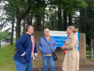 Hannah with residents next to the Princess Royal Hospital sign discussing their experiences. 